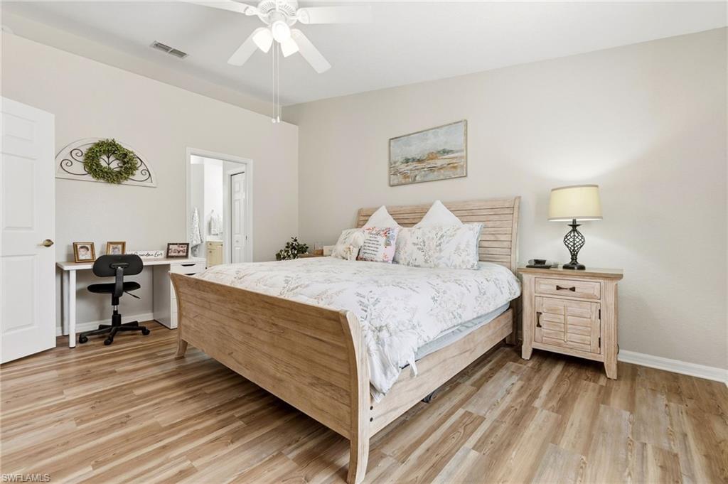 Bedroom with light wood-style flooring, ceiling fan, a desk, and connected bathroom