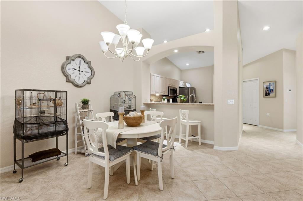 Dining space featuring high vaulted ceiling, arched walkways, a chandelier, light tile patterned flooring, and recessed lighting