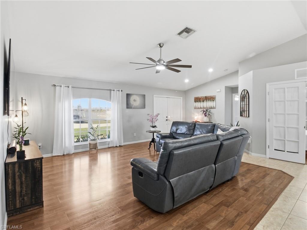 Living area featuring light wood-type flooring, vaulted ceiling, ceiling fan, and recessed lighting and DEN entry door.