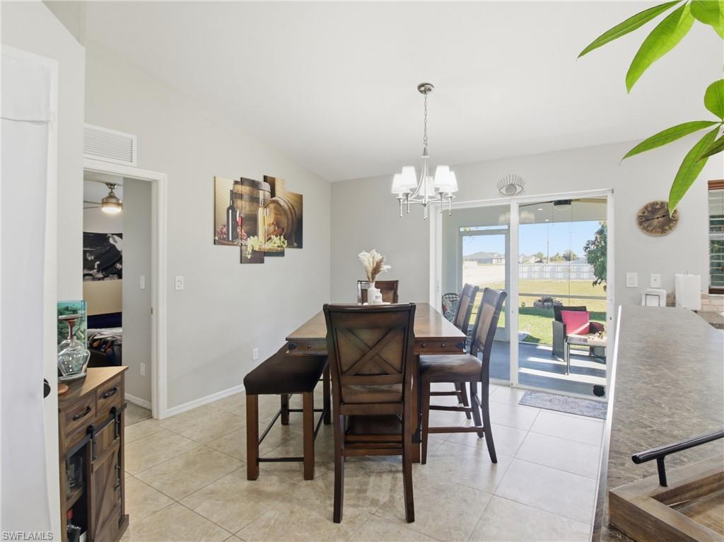 Dining space featuring light tile patterned floors, a chandelier, and vaulted ceiling