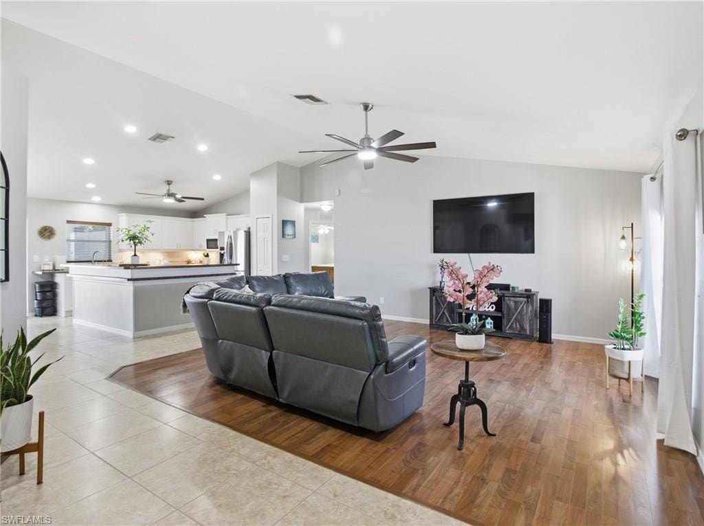 Living room with vaulted ceiling, light tile patterned floors, and ceiling fan