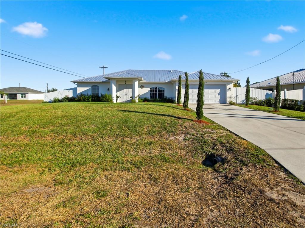 Front view of Single story home with a front lawn, concrete driveway, and metal roof.