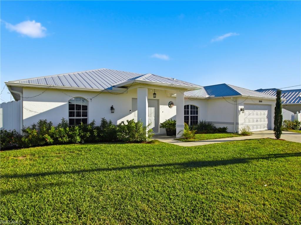 Ranch-style home with stucco siding, a front yard, an attached garage, and concrete driveway