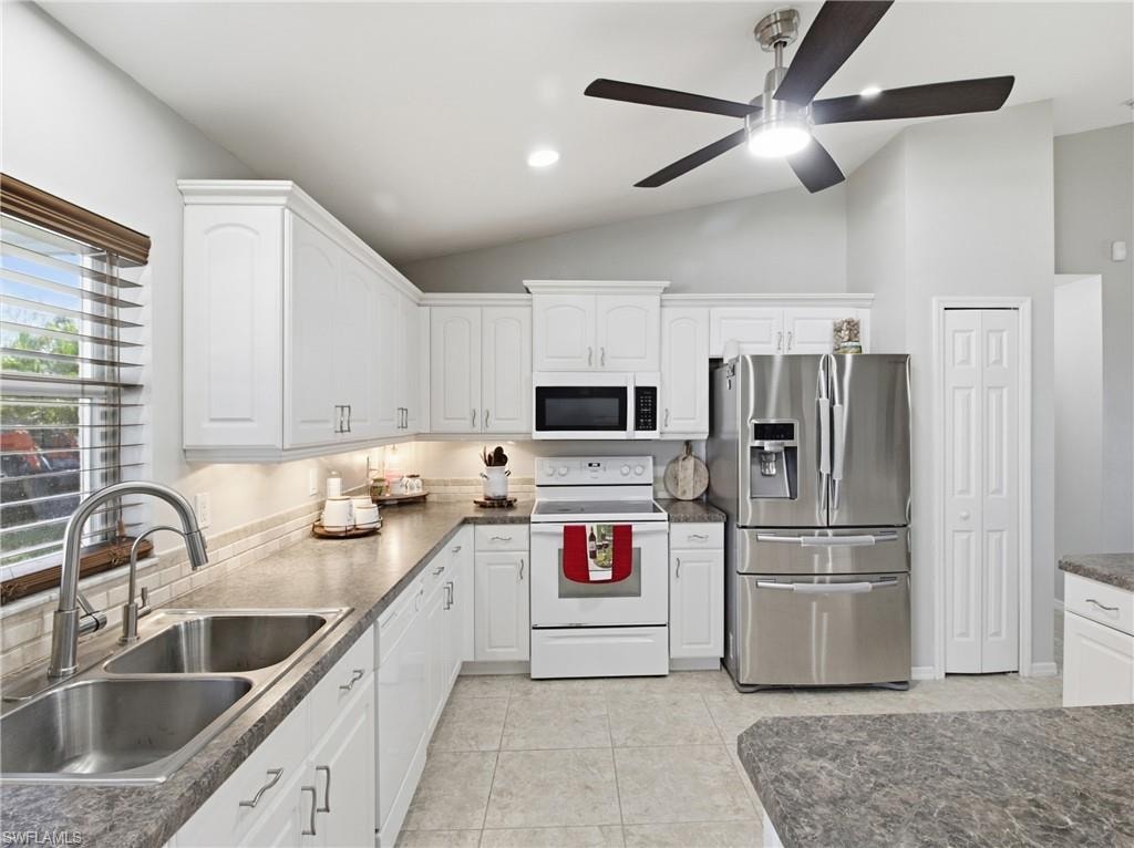 Kitchen with white appliances, white cabinets, recessed lighting, vaulted ceiling, and light tile patterned flooring
