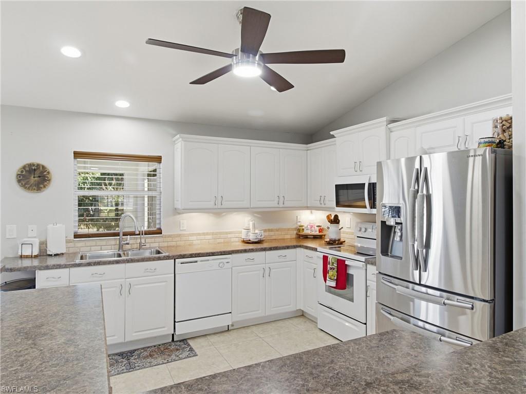 Kitchen with white appliances, white cabinetry, a ceiling fan, light tile patterned floors, and vaulted ceiling
