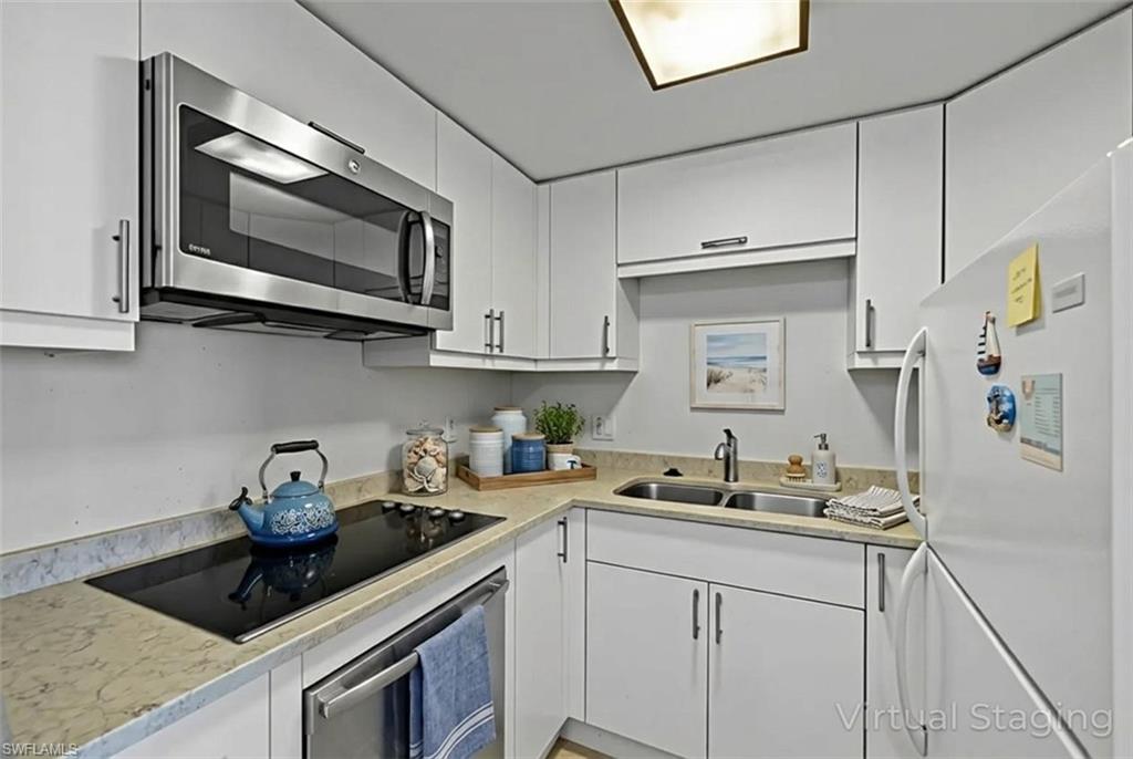 Kitchen with appliances with stainless steel finishes, white cabinets, and light stone countertops