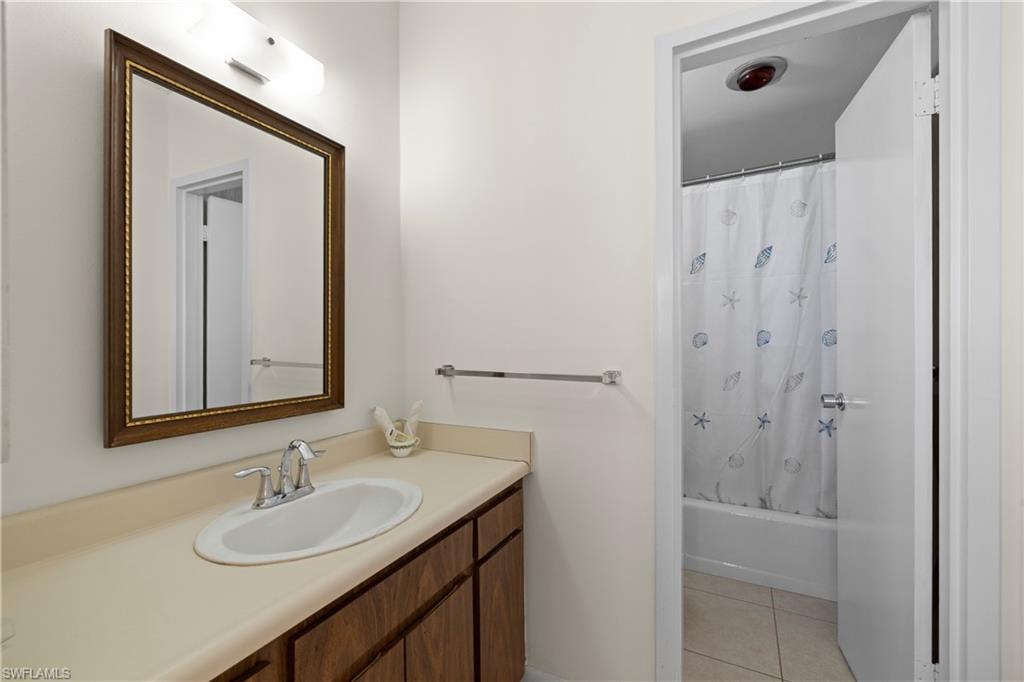 Bathroom featuring vanity, shower / bath combo with shower curtain, and light tile patterned flooring