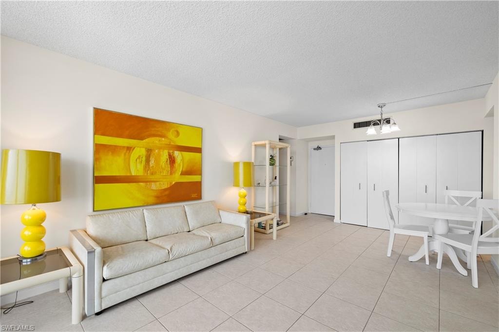 Living room featuring a textured ceiling, tile patterned flooring, and a chandelier