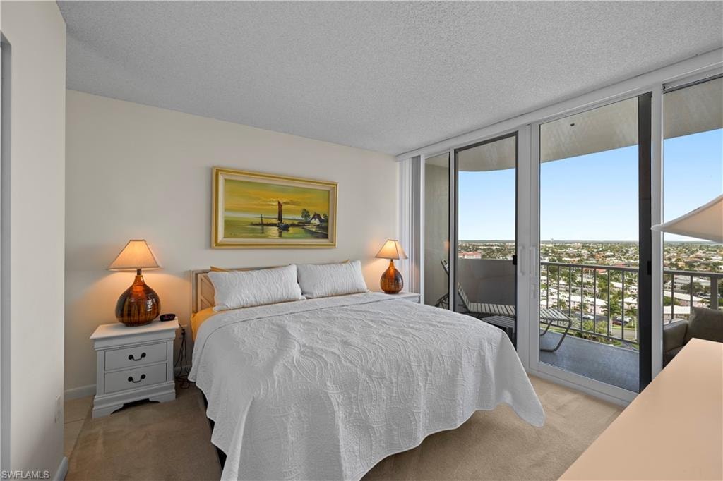 Carpeted bedroom featuring access to outside, a textured ceiling, and a wall of windows