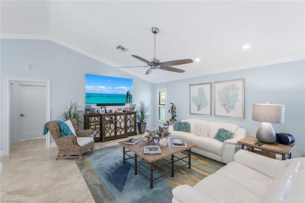 Living room featuring crown molding, ceiling fan, and vaulted ceiling