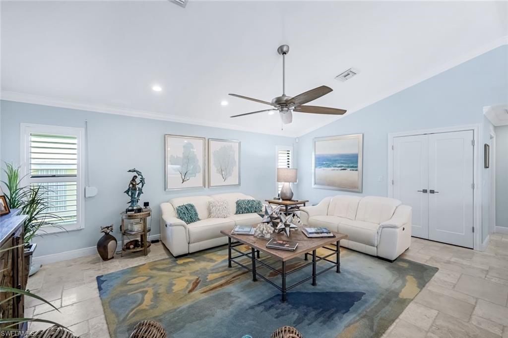 Living room featuring crown molding, vaulted ceiling, plantation shutters & ceiling fan.