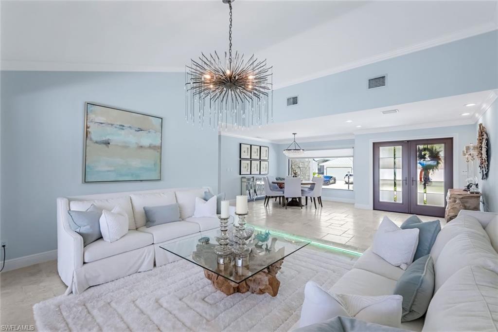Formal living room looking toward double door hurricane impact entry. Multi colored custom lighting on floor.