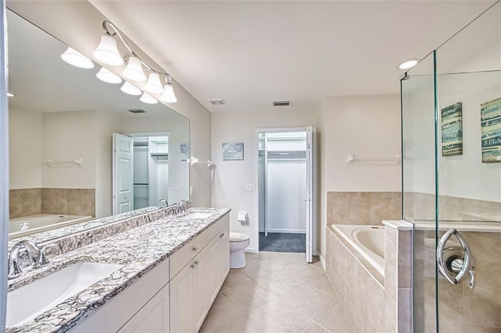 Bathroom with a garden tub, double vanity, light tile patterned floors, a walk in closet, and a shower stall