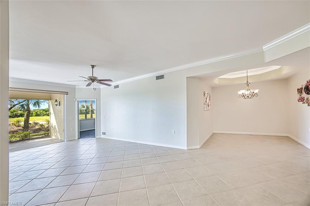 Empty room featuring light tile patterned flooring, ceiling fan, and a chandelier
