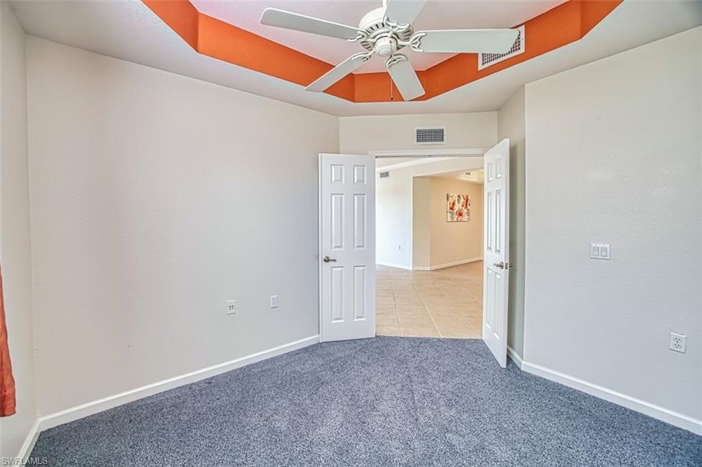 Unfurnished room featuring a tray ceiling, ceiling fan, and carpet flooring