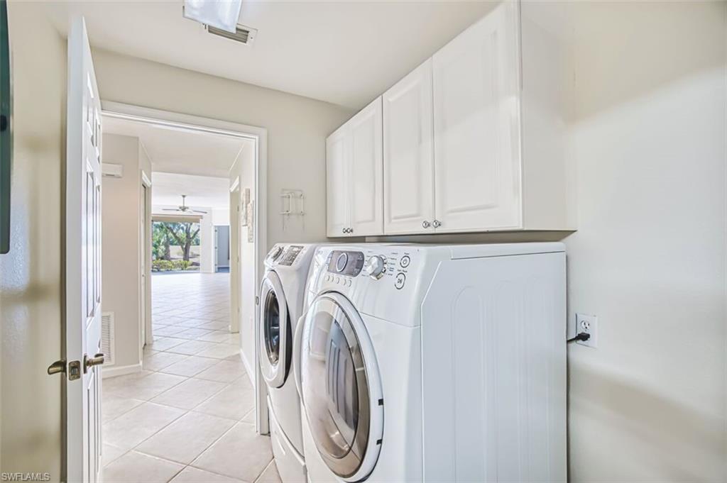 Laundry area featuring cabinet space, light tile patterned floors, and washing machine and clothes dryer