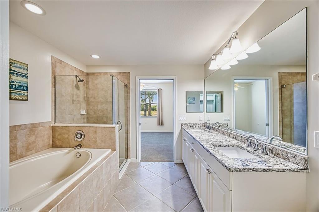 Bathroom with double vanity, a shower stall, a bath, light tile patterned floors, and light carpet