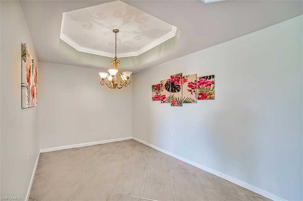 Spare room with crown molding, a tray ceiling, and a chandelier