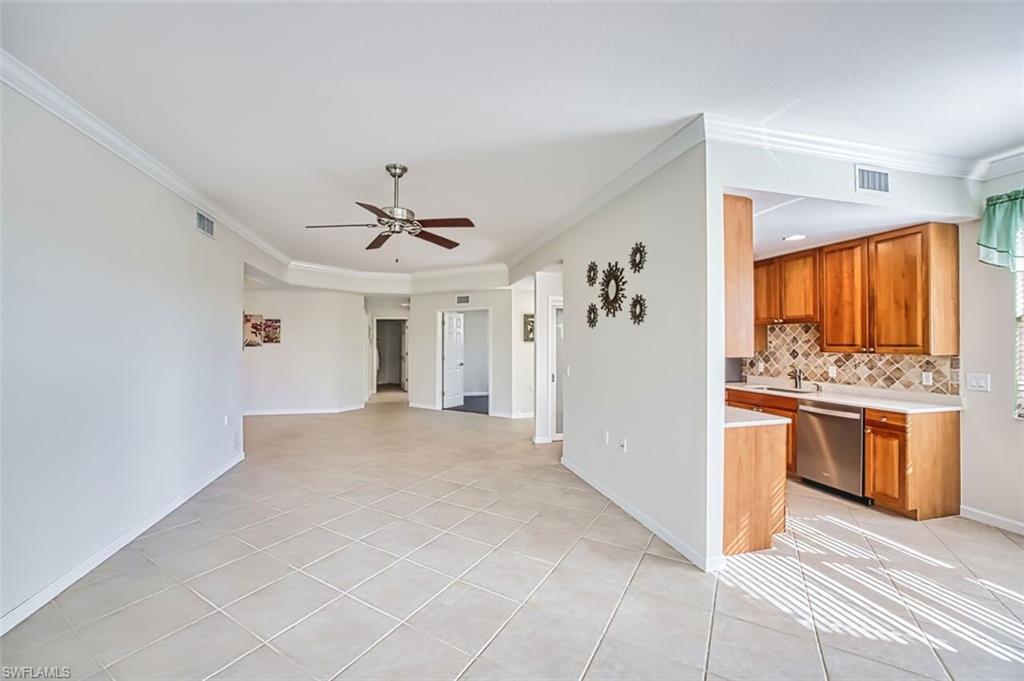 Kitchen with light countertops, light tile patterned flooring, crown molding, open floor plan, and brown cabinets