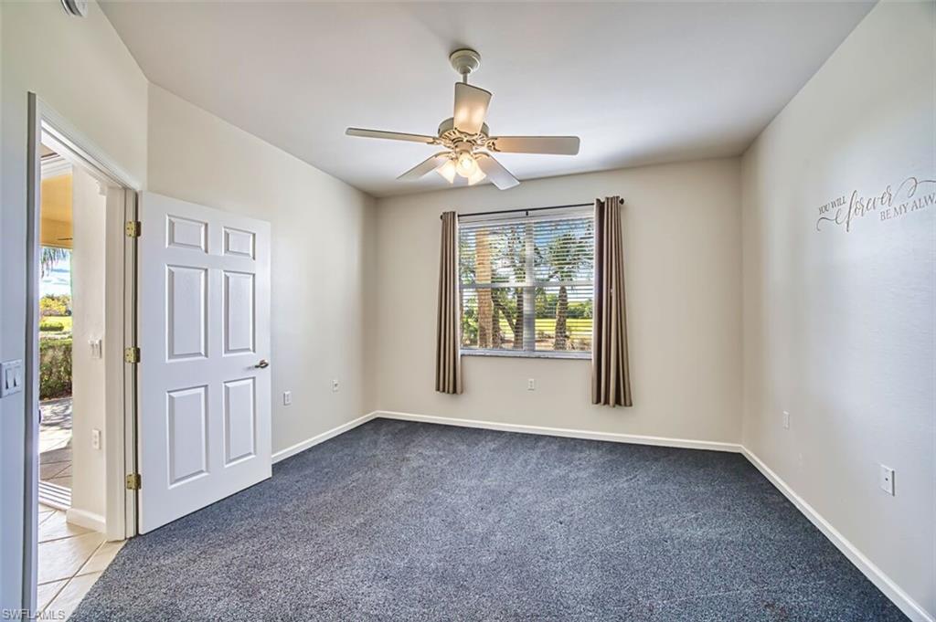 Unfurnished room featuring dark colored carpet and a ceiling fan