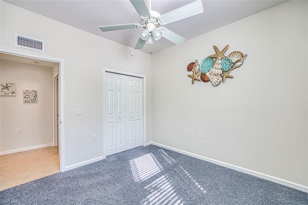 Unfurnished bedroom with carpet, a ceiling fan, a closet, and tile patterned floors