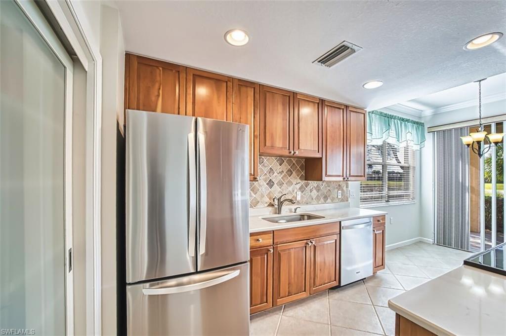 Kitchen with brown cabinetry, stainless steel appliances, ornamental molding, pendant lighting, and recessed lighting