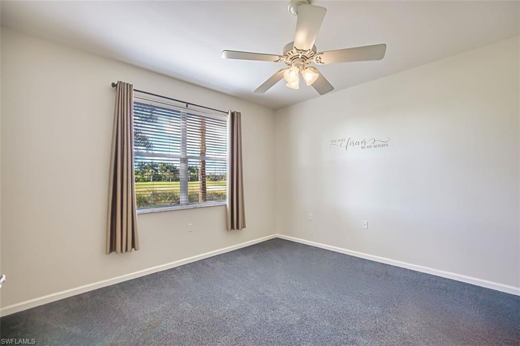Carpeted spare room featuring baseboards and ceiling fan