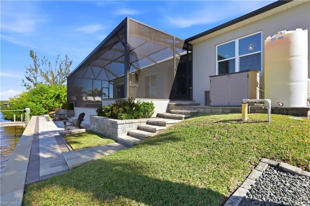 Rear view of property featuring a lanai, a sunroom, stucco siding, and a lawn