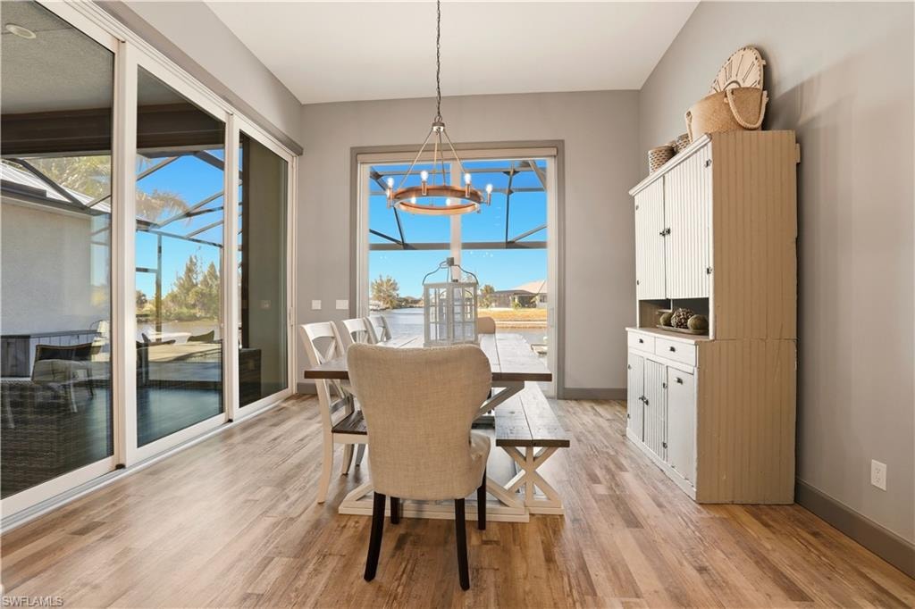 Dining space featuring a chandelier and light wood finished floors with Sliding Door to the Pool area and to the covered lanai area.