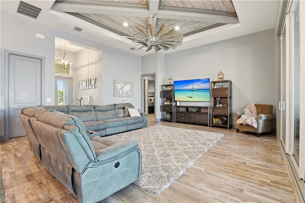 Living room with a wood ceiling with exposed beams, a chandelier, recessed lighting, light wood-style floors, and a high ceiling.