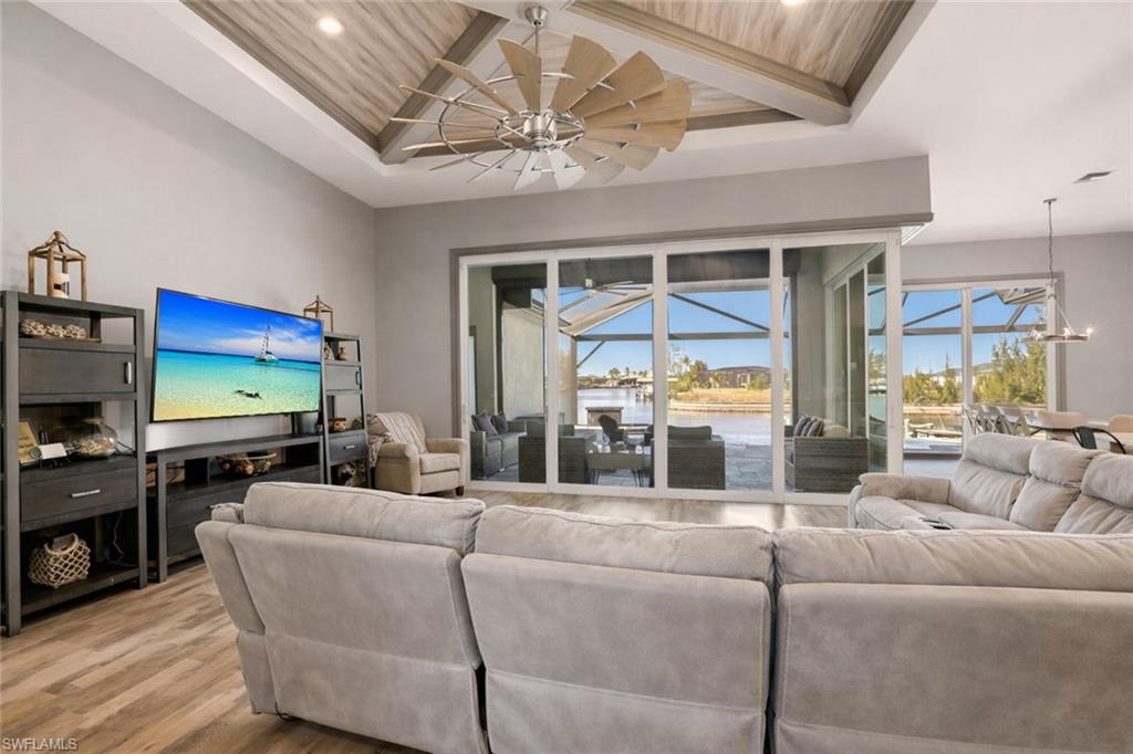 Living area with healthy amount of natural light, a covered lanai, light wood finished floors, recessed lighting, and a wooden ceiling with custom millwork exposed beams.