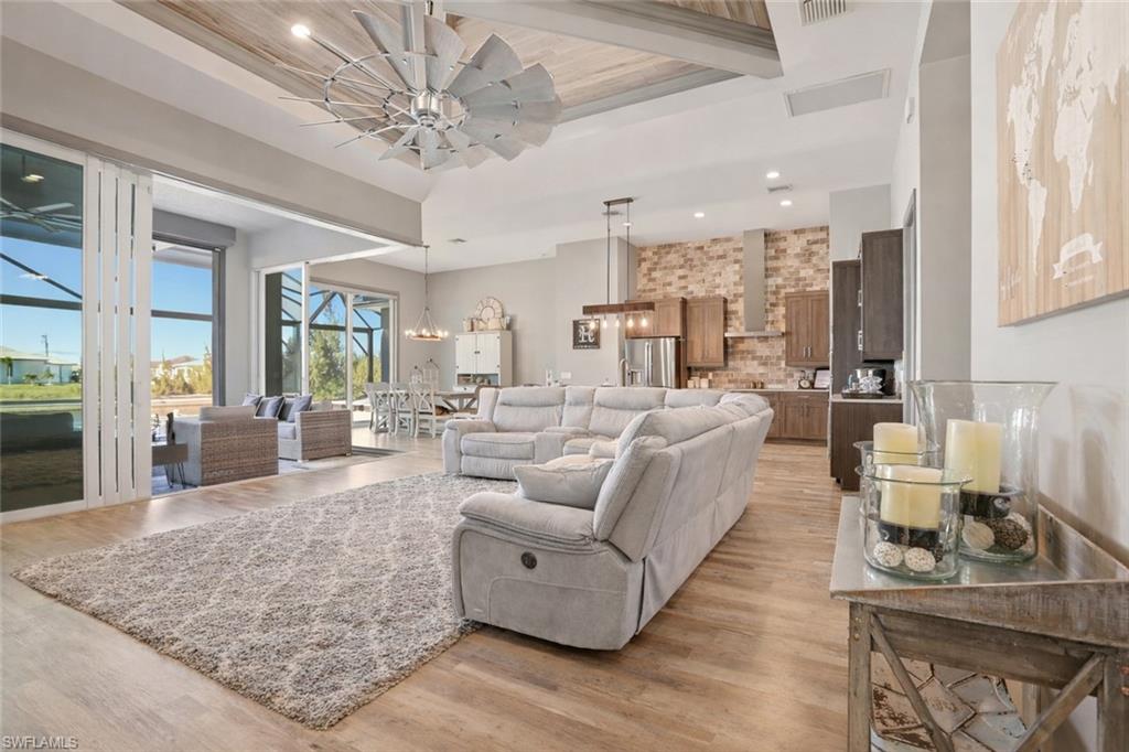 Living room featuring light wood finished floors, recessed lighting, ceiling fan, a towering ceiling, and a gorgeous fan to complement the decor.  Notice the Zero Glass Sliding Door that opens up the outdoors to your indoor space.