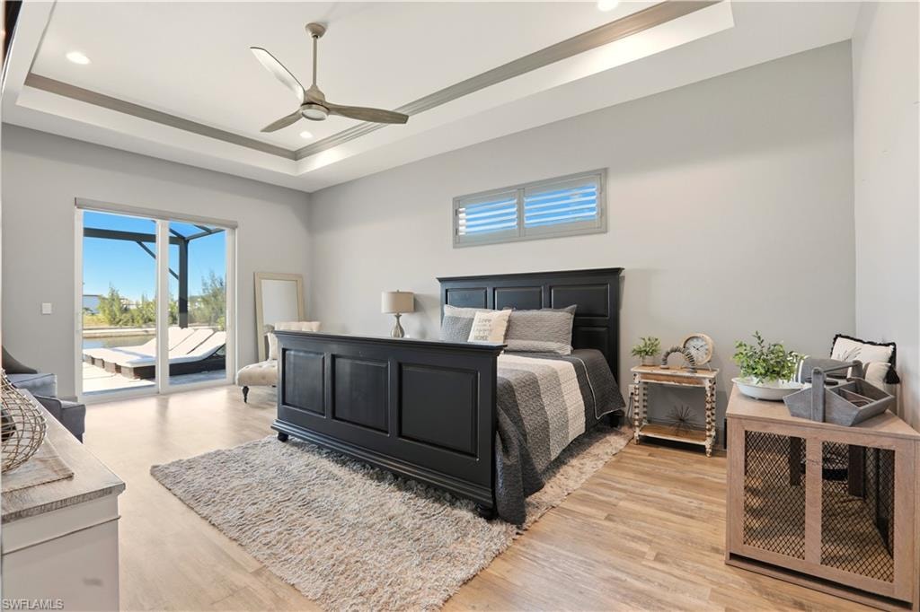 Primary Bedroom featuring access to outside, ceiling fan, light wood-style floors, recessed lighting, and a raised ceiling