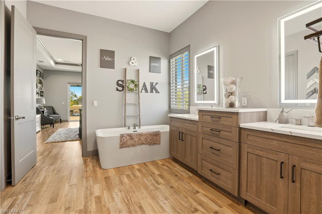 Primary Full bath featuring light wood-type flooring, a freestanding tub, vanity, and plenty of natural light