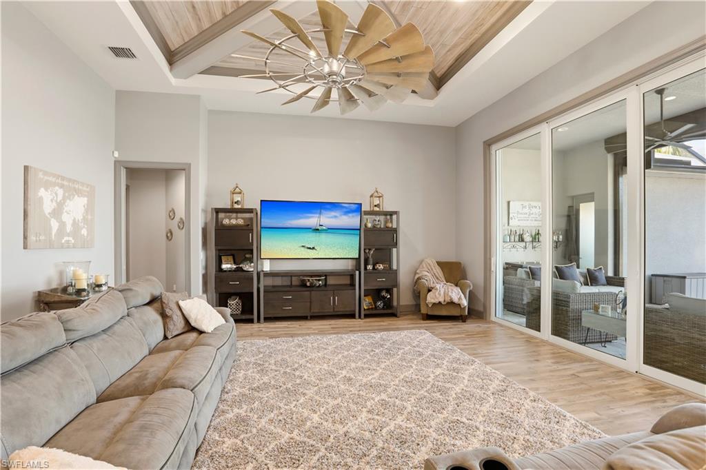 Sit back and relax while you watch TV and the outdoor activity at the same time.  Living room featuring a ceiling fan, wood finished floors, and a tray ceiling.