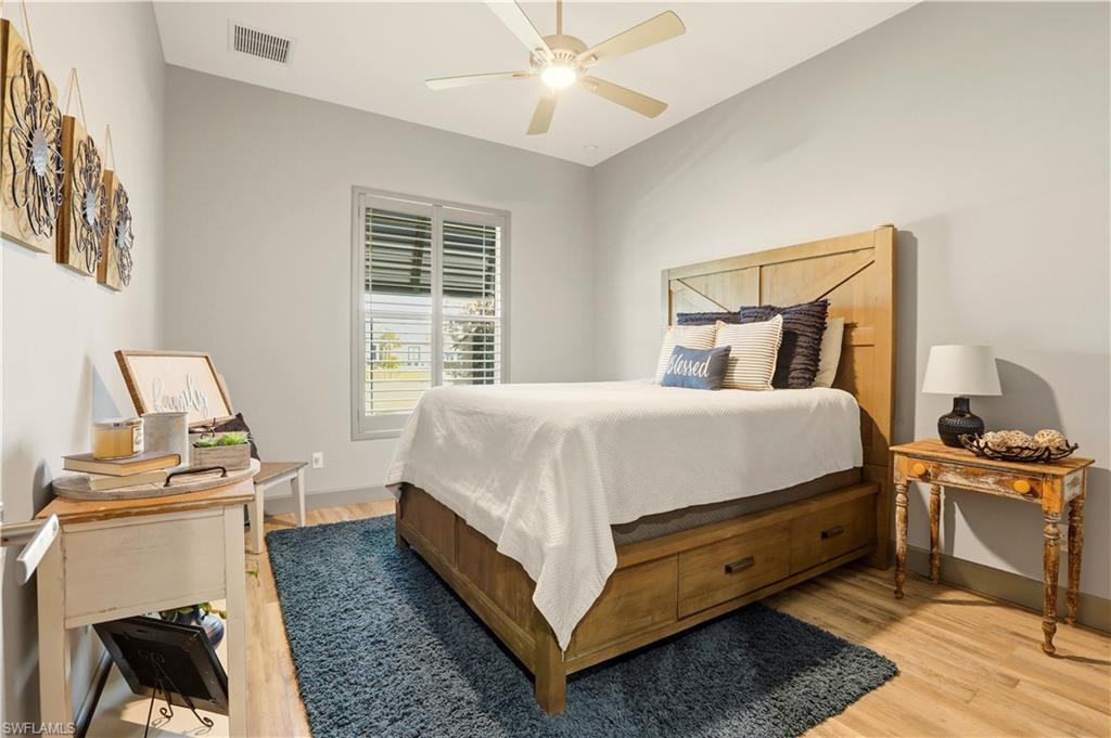 3rd Bedroom with light wood-style floors and a ceiling fan.  Notice the plantation shutters.