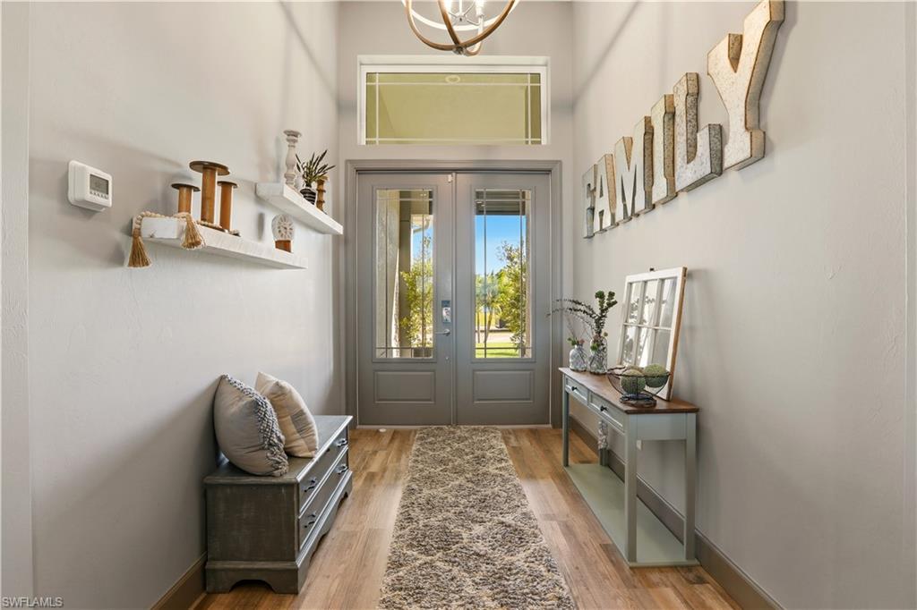 Doorway to outside featuring wood finished floors, french doors, a chandelier, and a towering ceiling.