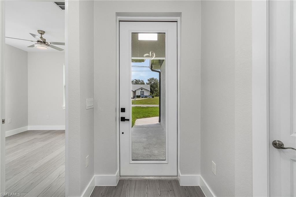 Doorway with wood finished floors and a ceiling fan