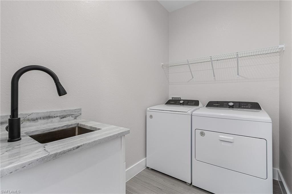 Laundry room with washer and dryer, light wood-type flooring, and a textured wall
