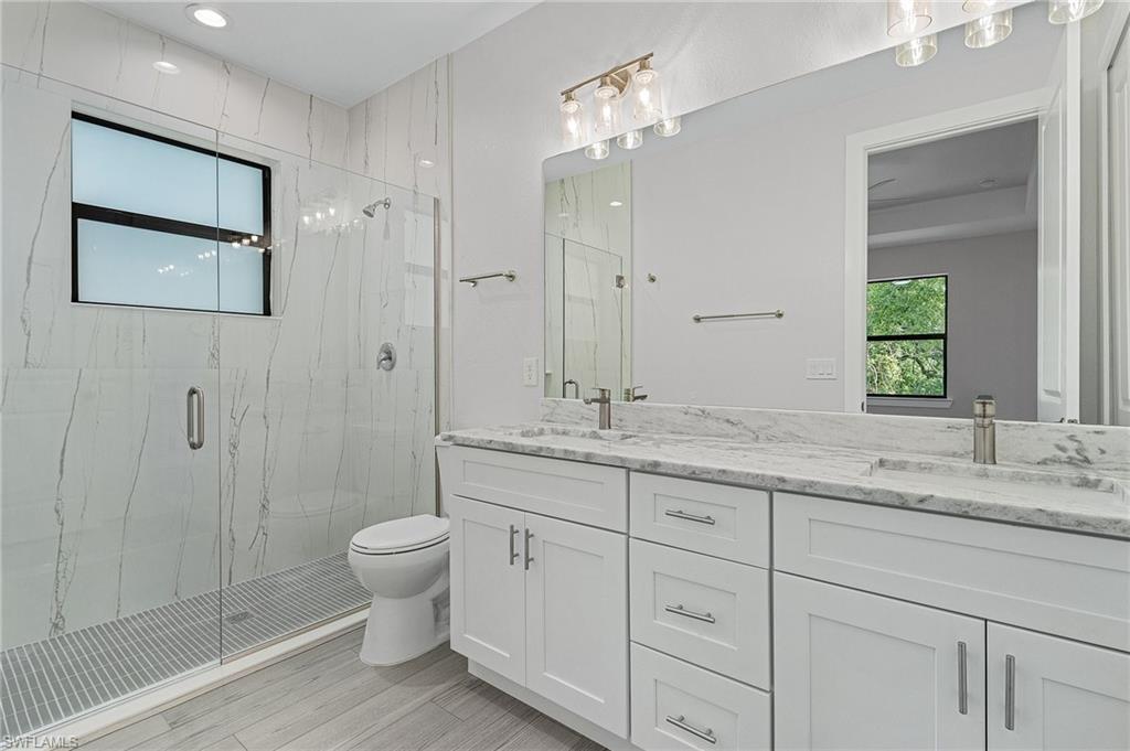 Full bathroom featuring a marble finish shower and double vanity