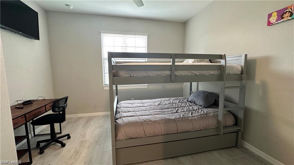 Bedroom featuring a ceiling fan, light wood finished floors, and baseboards