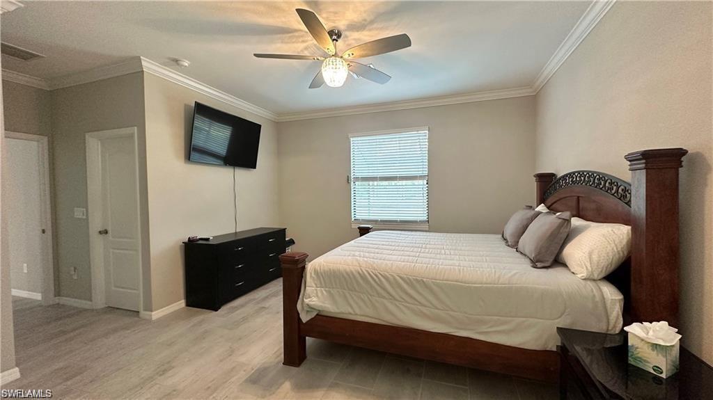 Bedroom featuring light wood finished floors, baseboards, a ceiling fan, and crown molding