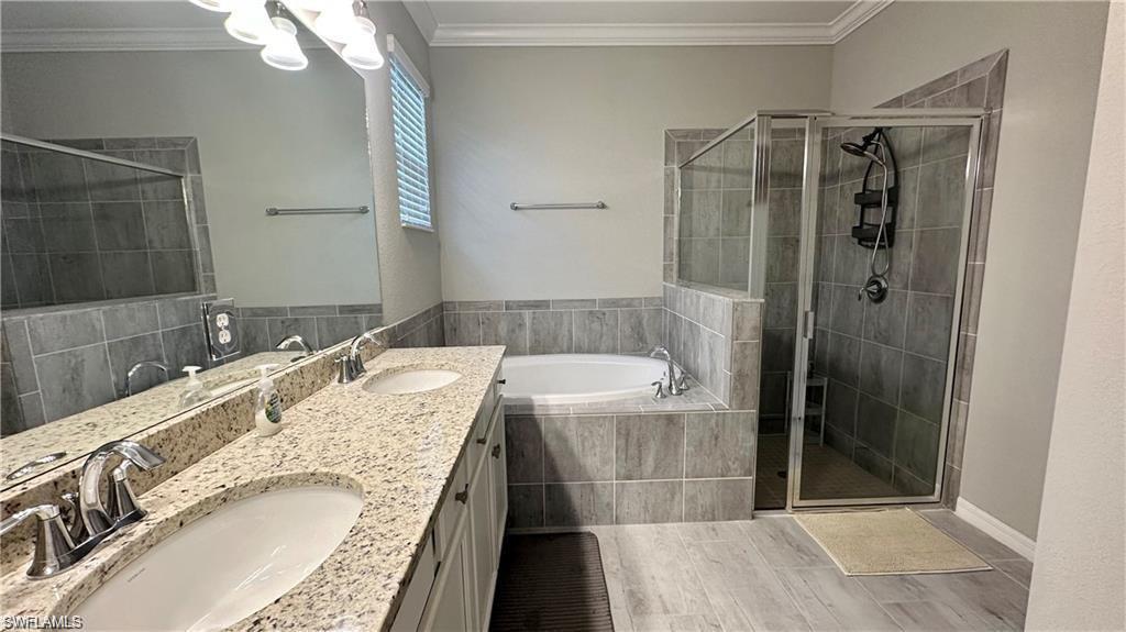 Bathroom featuring a sink, a bath, and crown molding