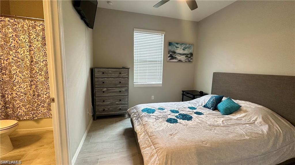 Bedroom featuring ensuite bath, a ceiling fan, and baseboards