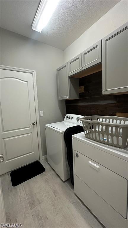Laundry area featuring a textured ceiling, washing machine and dryer, and cabinet space