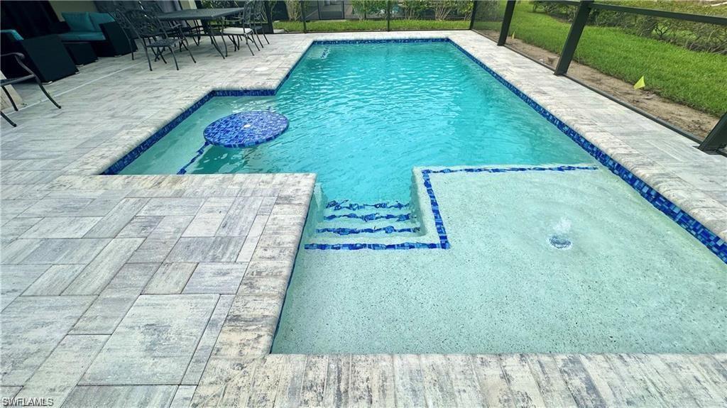 Outdoor pool featuring a patio area and glass enclosure