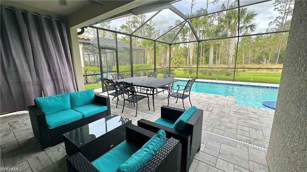 View of patio featuring glass enclosure, an outdoor pool, and an outdoor hangout area
