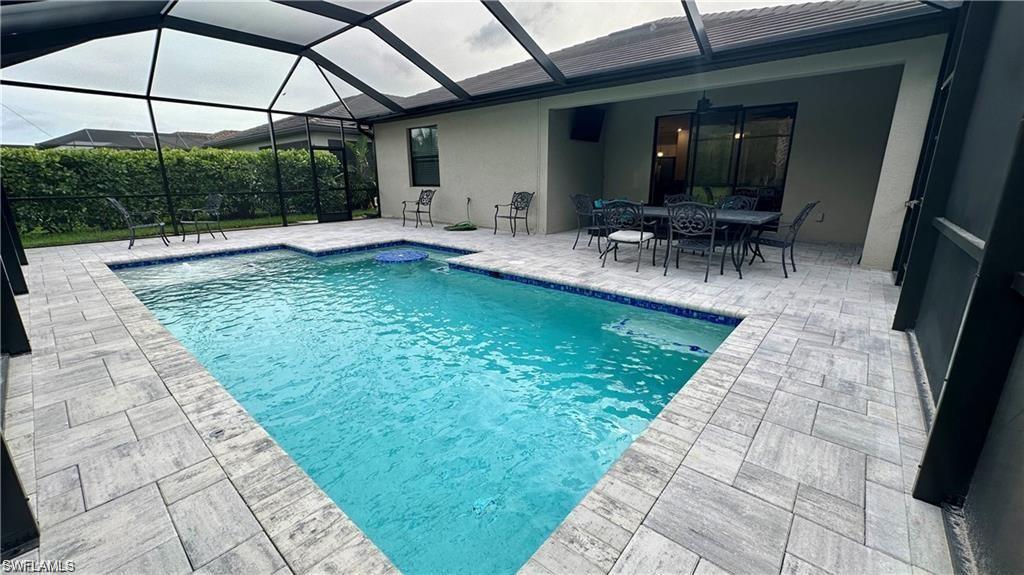 View of pool with glass enclosure, a patio area, and a fenced in pool