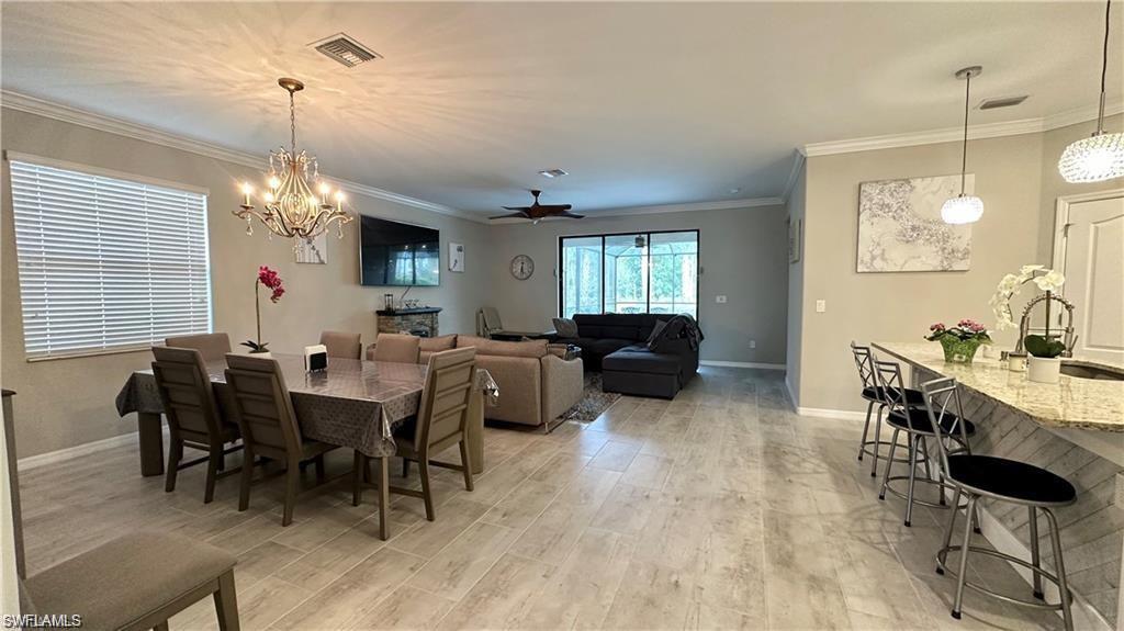 Dining room with ornamental molding, light wood-type flooring, visible vents, and baseboards