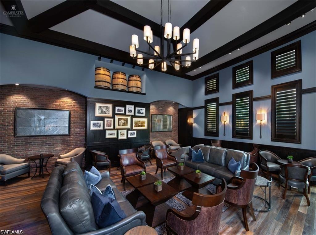 Home theater room featuring a chandelier, beamed ceiling, brick wall, and wood finished floors